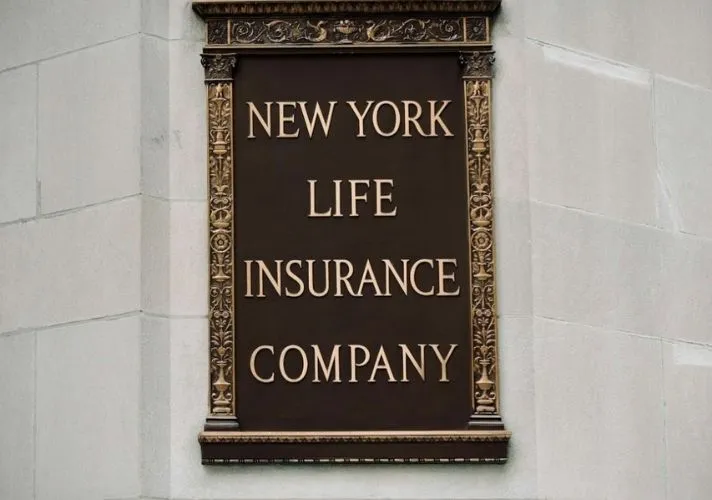 Bronze plaque on a stone wall displaying the words “New York Life Insurance Company” in engraved capital letters with decorative borders.