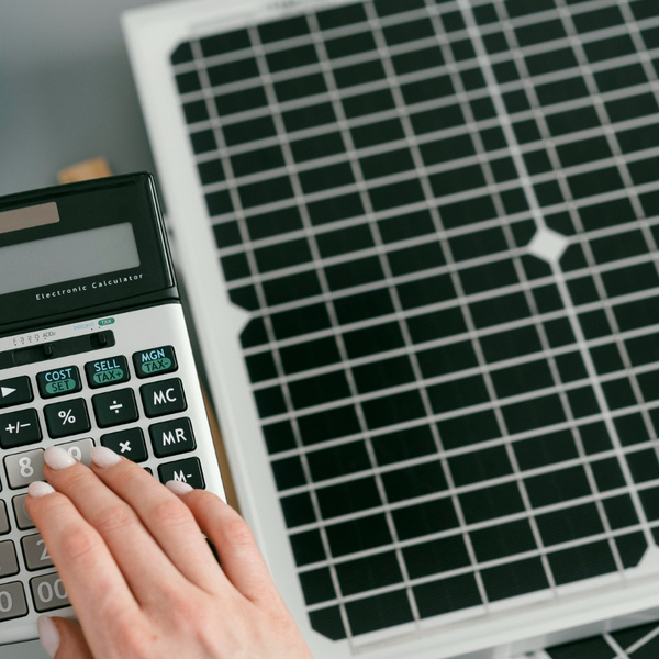 Calculator and solar panel used to illustrate solar energy sizing calculations for determining system requirements